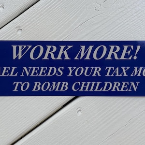 May include: A rectangular blue bumper sticker with white text that reads: WORK MORE! ISRAEL NEEDS YOUR TAX MONEY TO BOMB CHILDREN. The bottom right corner includes the small text SKELETON HOUSE. The sticker has a smooth, glossy finish.