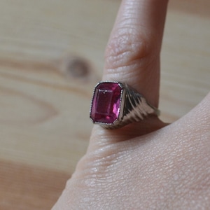 May include: A silver ring with a large, rectangular, pink gemstone.