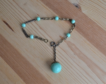 Peut inclure: Un bracelet délicat en chaîne dorée et turquoise avec un grand pendentif turquoise. Le bracelet a un design simple avec de petites perles turquoise et une chaîne dorée.