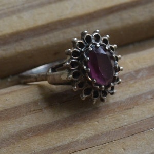 May include: A silver ring with a purple gemstone set in a filigree design.