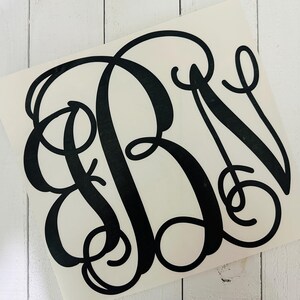 May include: Black monogram decal featuring the letters RBN in a classic, elegant script. The decal is on a white background, with a glossy finish. The design is suitable for various applications, such as car windows, laptops, or home decor.
