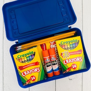 May include: A blue plastic school supply box containing two yellow boxes of 24 Crayola crayons, two orange Elmer's washable school glue sticks, and several yellow wooden pencils with pink erasers. The supplies are arranged inside the open container.