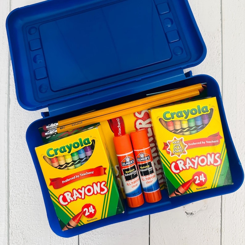 May include: A blue plastic school supply box containing two yellow boxes of 24 Crayola crayons, two orange Elmer's washable school glue sticks, and several yellow wooden pencils with pink erasers. The supplies are arranged inside the open container.
