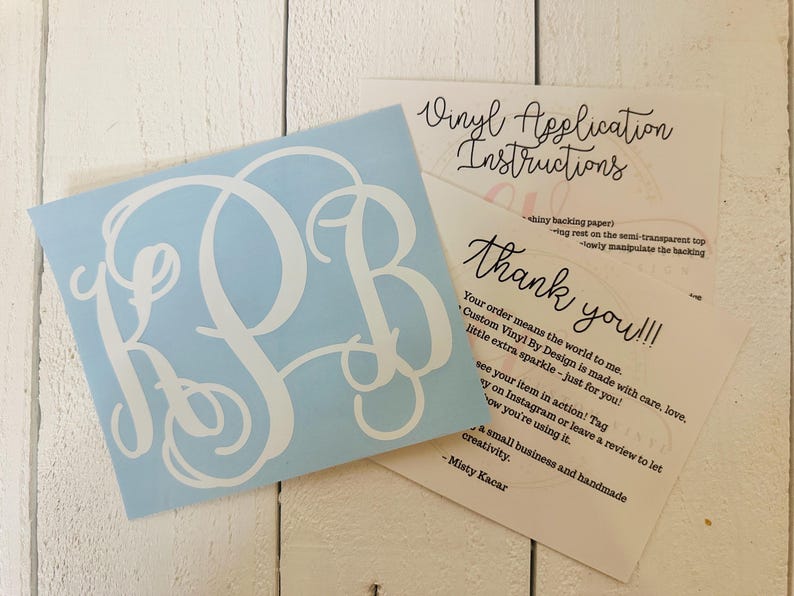 May include: A light blue vinyl decal with a white monogram of the letters R, S, and B. The decal is accompanied by two cards with handwritten text, including "Vinyl Application Instructions" and "thank you!!!".