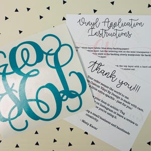 May include: A teal monogram vinyl decal with a cursive font, alongside instructions and a thank you note. The decal features the letters E, O, and L. The background is a cream color with black triangles.