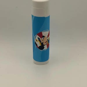 May include: A cylindrical lip balm tube with a white cap and a light blue body. The label features a graphic of a cartoon mouse character wearing a captain's hat, positioned inside a red and white striped life preserver ring design.