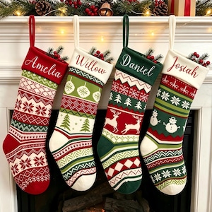 Peut inclure: Quatre chaussettes de Noël personnalisées avec des motifs en tricot rouge, vert et blanc. Chaque chaussette porte un prénom : Amelia, Willow, Daniel ou Josiah. Les motifs incluent des flocons, des sapins, des rennes et des bonshommes de neige.