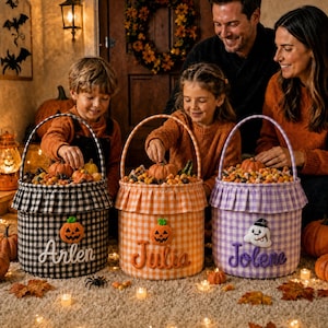 May include: Three fabric Halloween baskets with ruffled rims and handles. The black and white gingham basket features a pumpkin and the name Arlen. The orange gingham basket has a pumpkin and the name Julia. The purple gingham basket has a ghost and the name Jolene.