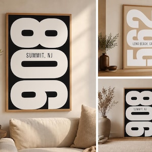 May include: A framed vertical wall art print featuring large white numbers 908 with the text SUMMIT, NJ in black, and a second print showing white numbers 562 with the text LONG BEACH, CA on a tan background, both displayed in a home setting.