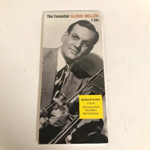 May include: A 2-CD set titled The Essential Glenn Miller featuring a black and white portrait of Glenn Miller holding a trombone. A yellow sticker on the cover reads Big Band At Its Best! 2-CD Set That Features All Of Glenn Miller's Most Loved Songs.