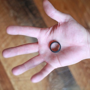 Op de afbeelding: Een zwarte siliconen ring op een open hand.