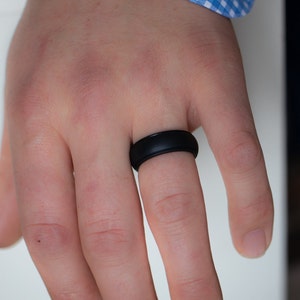 Op de afbeelding: Een zwarte siliconen ring aan een vinger.