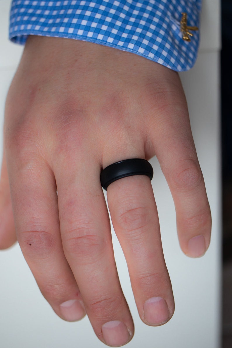 Op de afbeelding: Een zwarte siliconen ring aan een vinger.