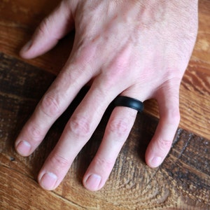 Op de afbeelding: Een zwarte siliconen ring gedragen aan een vinger.