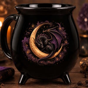 Può includere: Una tazza in ceramica nera a forma di calderone con un manico rotondo e tre piccoli piedini. La parte anteriore presenta un grafico dettagliato di un drago scuro con ali viola rannicchiato in una mezzaluna dorata, circondato da nuvole viola.