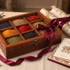 May include: A rectangular wooden spice box with nine compartments containing various colourful spices, secured with a metal latch and tied with a deep red ribbon. A small card reads To Someone Special With Love, accompanied by floral patterned paper.