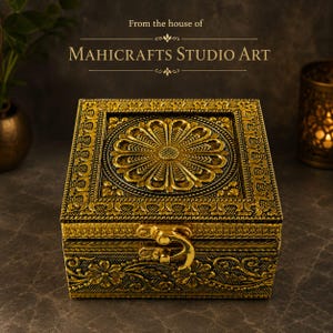 Könnte beinhalten: Eine quadratische, goldfarbene Zierbox mit detaillierten Blumenprägungen auf dem Deckel und den Seiten. Die Box verfügt über ein zentrales, kreisförmiges Blumenmotiv auf dem Deckel und einen Metallverschluss. Text: From the house of MAHICRAFTS STUDIO ART.