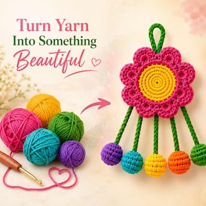 May include: A crochet wall hanging featuring a large pink and yellow flower with five dangling green stems ending in colorful spheres. Beside it are yarn balls in pink, yellow, green, blue, and purple, a wooden crochet hook, and the text Turn Yarn Into Something Beautiful.