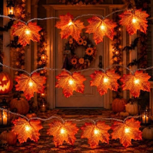 May include: A string of decorative lights featuring artificial maple leaves in shades of orange, red, and yellow. Each leaf is illuminated from behind by a small light, creating a warm glow. The leaves are arranged in three horizontal rows.