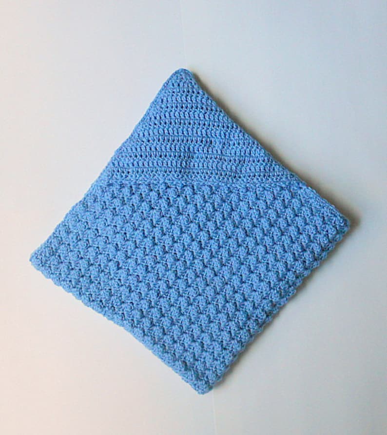 May include: A light blue crocheted baby blanket with a textured pattern.