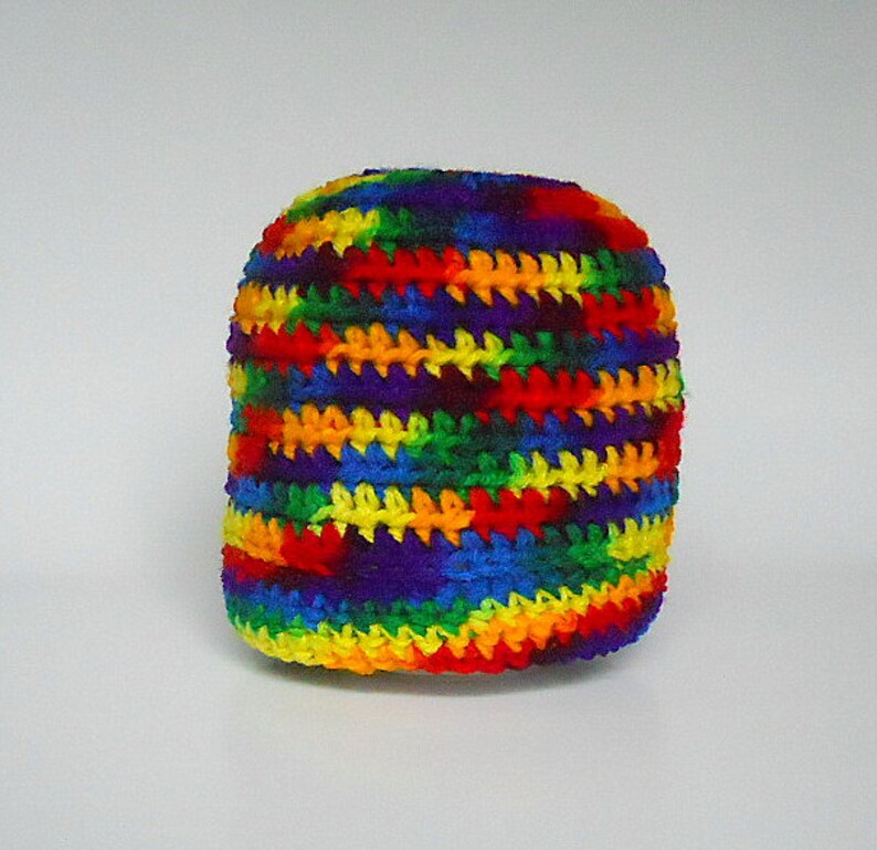 May include: A crocheted hat with a rainbow striped pattern. The hat is made with a variety of colors, including red, orange, yellow, green, blue, indigo, and violet.