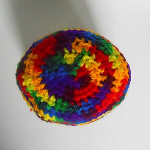 May include: A colorful crocheted hat with a rainbow pattern. The hat is made of yarn in shades of red, orange, yellow, green, blue, indigo, and violet.