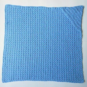 May include: A light blue crocheted baby blanket with a textured pattern.