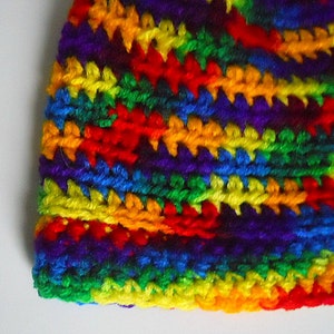 May include: A colorful crocheted hat with stripes of red, orange, yellow, green, blue, indigo, and violet.