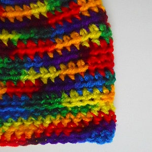 May include: A colorful crocheted hat with a rainbow pattern. The hat is made with different shades of red, orange, yellow, green, blue, and purple yarn.