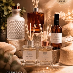May include: A collection of home fragrance products including a frosted glass bottle, an amber glass bottle, and two clear glass reed diffusers with wooden sticks. Labels read Fresh & Fragrant Essentials, Reed Diffusers, Lavender, Si, and Lemongrass.
