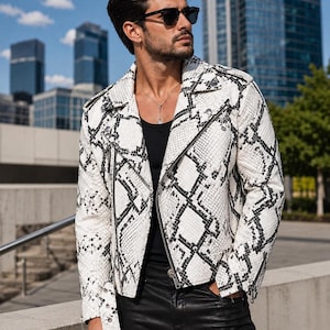 Peut inclure: Une veste de moto à motif peau de serpent blanc et noir avec un revers cranté, des fermetures éclair en métal argenté et une ceinture à la taille. La veste est portée sur un débardeur noir uni et associée à un pantalon noir, style motard classique.
