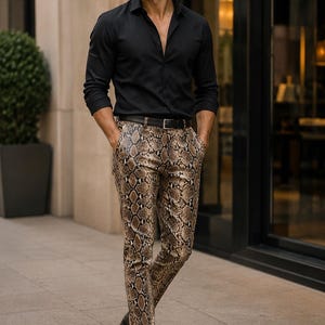 May include: A black long-sleeved button-down shirt paired with slim-fit trousers featuring a brown and black snakeskin print pattern. The outfit includes a black leather belt with a silver buckle and black leather tassel loafers.