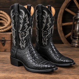 May include: A pair of black cowboy boots featuring a textured crocodile-skin pattern on the foot and a square toe. The tall shaft is made of smooth black leather with intricate silver-grey decorative stitching and pull tabs at the top.