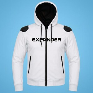 May include: A white zip-up hoodie featuring a black interior hood lining, black shoulder panels, and black trim along the zipper and pockets. The word EXPANDER is printed in bold black capital letters across the chest, accompanied by black drawstrings.