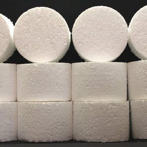 May include: A collection of white, cylindrical objects, arranged in rows. The objects have a textured surface and are stacked in a grid-like pattern. The top row consists of four circular pieces.