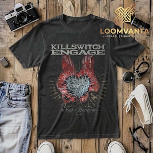 May include: A charcoal grey short-sleeve t-shirt featuring the text Killswitch Engage at the top and The End of Heartache at the bottom. The central graphic depicts two red hands cupping a silver heart shape covered in sharp metal spikes.