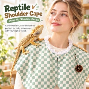 Peut inclure: Une cape d'épaule à carreaux vert clair et blanc avec une bordure en dentelle blanche autour de l'encolure, un petit bouton blanc et une breloque en forme de pomme de pin brune. Le texte indique : Reptile Shoulder Cape, Stand-Up Shoulder Design.