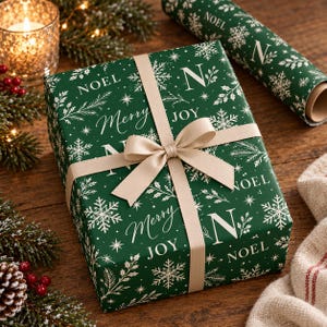 May include: A rectangular gift box wrapped in dark green paper featuring a white pattern of snowflakes, sprigs, and the text Noel, Merry, and Joy. The box is tied with a smooth, light beige ribbon tied in a centered bow on top.