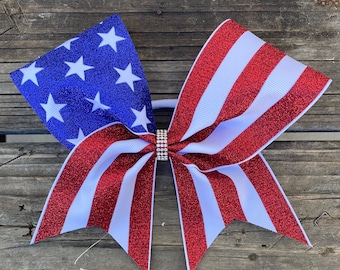 Laço de torcida com glitter: Fita com estrelas e listras vermelhas, brancas e azuis, no estilo americano.