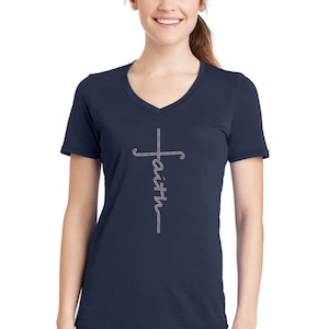 Puede incluir: Una camiseta azul marino de cuello en V con una cruz de strass y la palabra "fe" escrita verticalmente en el centro de la cruz.