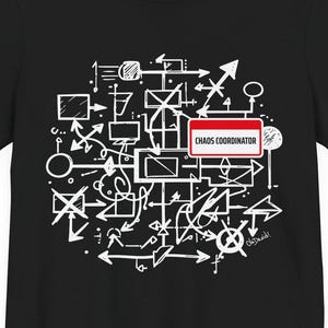 Pode incluir: Uma t-shirt preta de manga curta com uma impressão gráfica branca de linhas, setas e formas geométricas abstratas. Uma etiqueta retangular vermelha e branca está centrada no design com o texto "CHAOS COORDINATOR" impresso a preto.