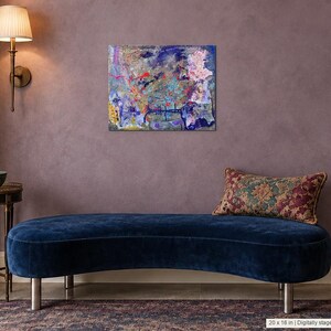 May include: A rectangular canvas painting featuring an abstract composition of layered blue, purple, pink, and yellow paint splatters and marks. The artwork is displayed on a wall above a curved navy blue velvet bench with a patterned throw pillow.