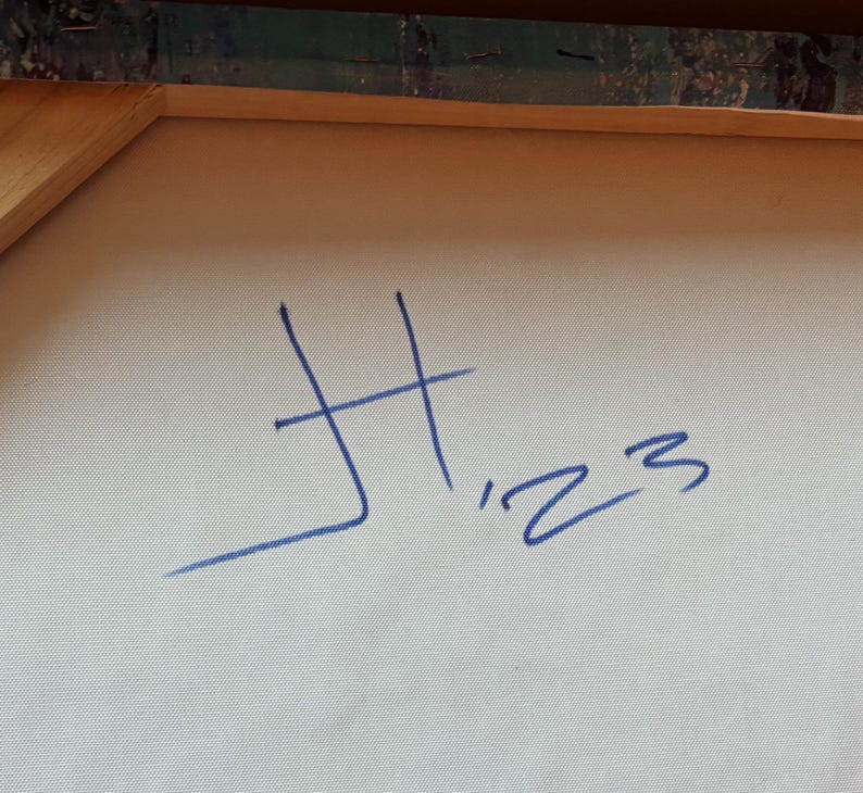 May include: A light-colored canvas stretched over a wooden frame, featuring a blue handwritten signature that reads H '23. The texture of the woven fabric is visible, and the wooden stretcher bars are partially visible at the top edge of the canvas.