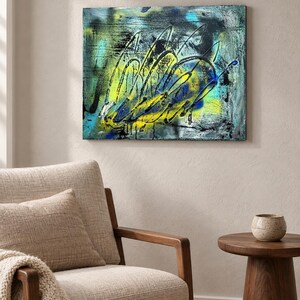 May include: A rectangular canvas painting featuring an abstract composition with vibrant yellow, bright cyan, and deep black paint. The artwork displays layered textures, energetic sweeping brushstrokes, and splattered paint effects across the surface.
