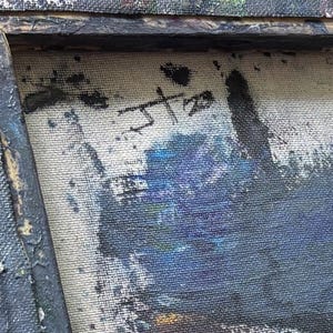 May include: A close-up of a textured canvas painting featuring a dark, weathered wooden frame. The artwork displays a signature with the letters JT and the number 20 in black paint. The composition includes deep blue, black, and white pigments.
