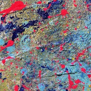 May include: A textured canvas painting featuring a vibrant abstract composition. The surface is layered with splatters and drips of bright neon pink paint over a base of deep navy blue, light turquoise, and metallic gold tones on a woven fabric.