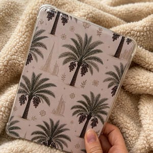 Puede incluir: Una funda protectora transparente para tableta con un patrón repetitivo de palmeras con dátiles, el Burj Khalifa y el Burj Al Arab sobre un fondo beige claro. El diseño incluye pequeños motivos de estrellas y hojas dispersos entre los monumentos.