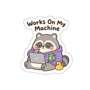 May include: A die-cut sticker featuring a grey raccoon wearing a purple hoodie and round glasses, sitting while using a laptop with a green checkmark on the screen. The raccoon holds a green soda can next to a yellow rubber duck. Text reads: Works On My Machine.