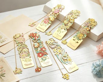 Può includere: Un set di sei segnalibri in metallo dorato con intricati intagli a forma di fiori e farfalle, arricchiti da smalti rosa, rossi, gialli e verdi. Ogni segnalibro presenta un ciondolo a catenella ed è inciso con i nomi Amanda, Oliver, Hannah, Nicole, Violet e Claire.