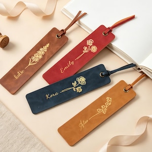 May include: Four rectangular leather bookmarks in brown, red, dark blue, and tan. Each features a gold-foiled floral illustration and a personalised name in cursive script: Katie, Emily, Kora, and Alice. Each bookmark has a metal eyelet and a leather cord.